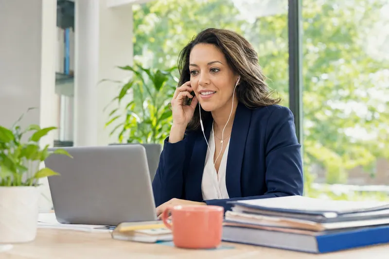 An outreach coordinator on a call at a campus office desk