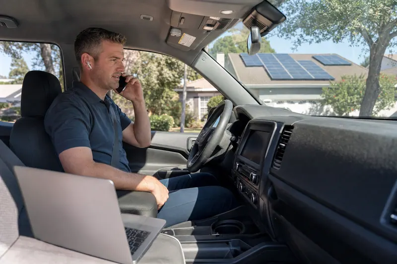 A home services rep on a call from his truck, solar panels on the roof behind